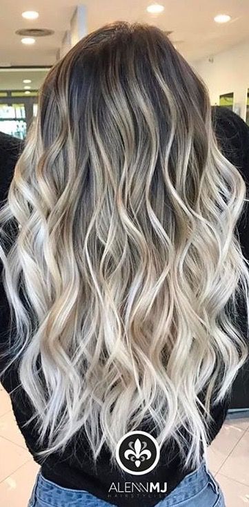 Cabelo longo com ondas em tons de loiro e castanho visto de costas em um ambiente interno iluminado.