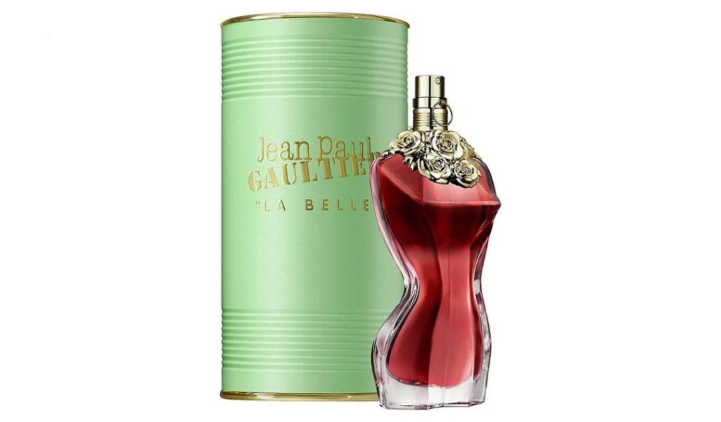 Frasco de perfume vermelho em forma de torso feminino ao lado de lata verde com detalhes dourados.