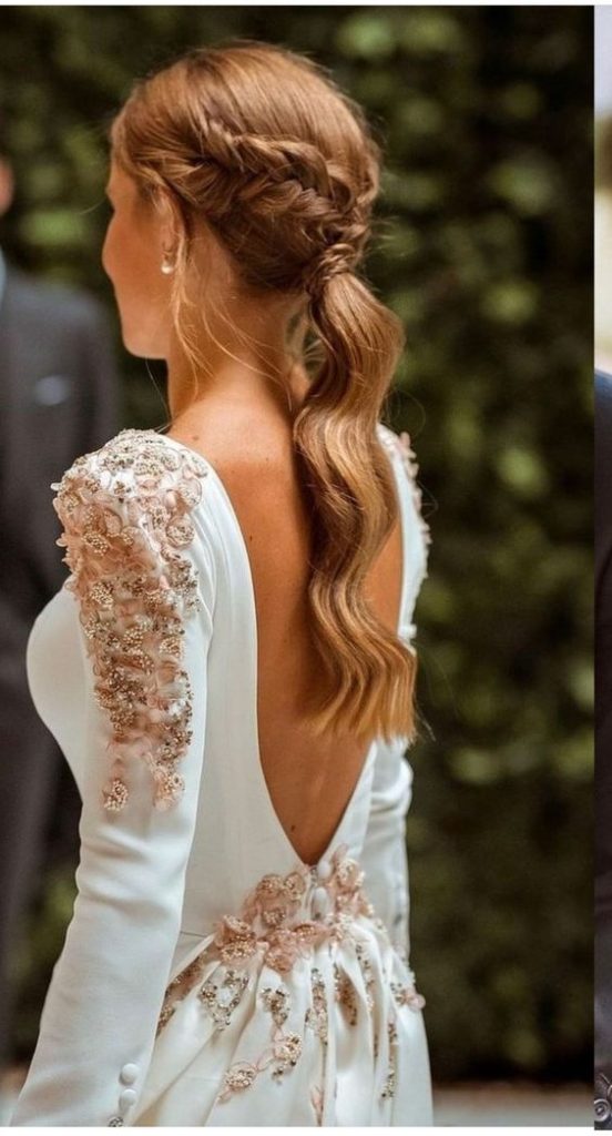 Pessoa com vestido branco de costas, cabelo trançado, em ambiente ao ar livre com fundo desfocado.