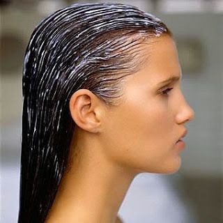 Pessoa de perfil com cabelo molhado, possivelmente com creme ou tratamento capilar aplicado.